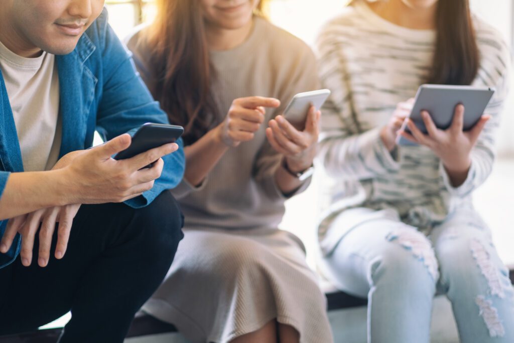 group people using looking mobile phone tablet pc while sitting together