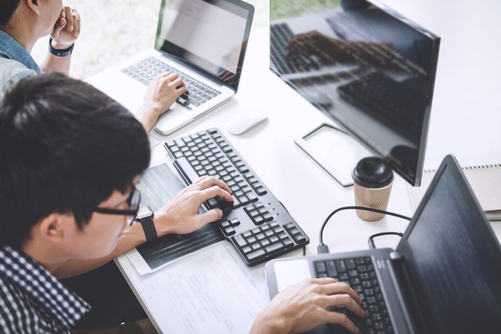 high angle view colleagues using laptops office desk